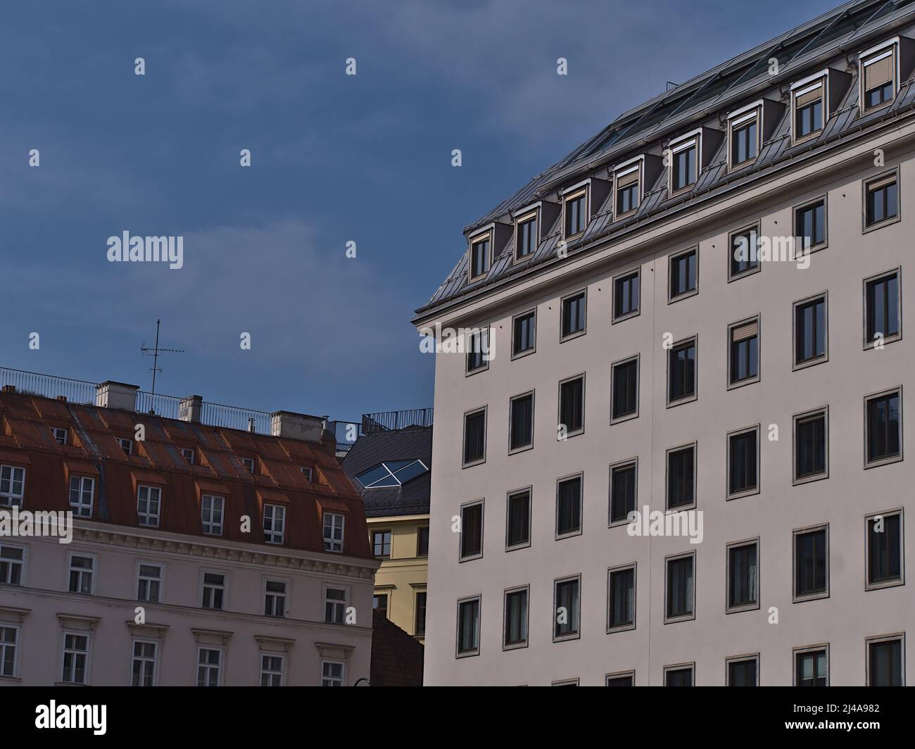 View of the top of characteristic old buildings in the historic center of Vienna, capital of Austria, on sunny day with blue sky. Stock Photo