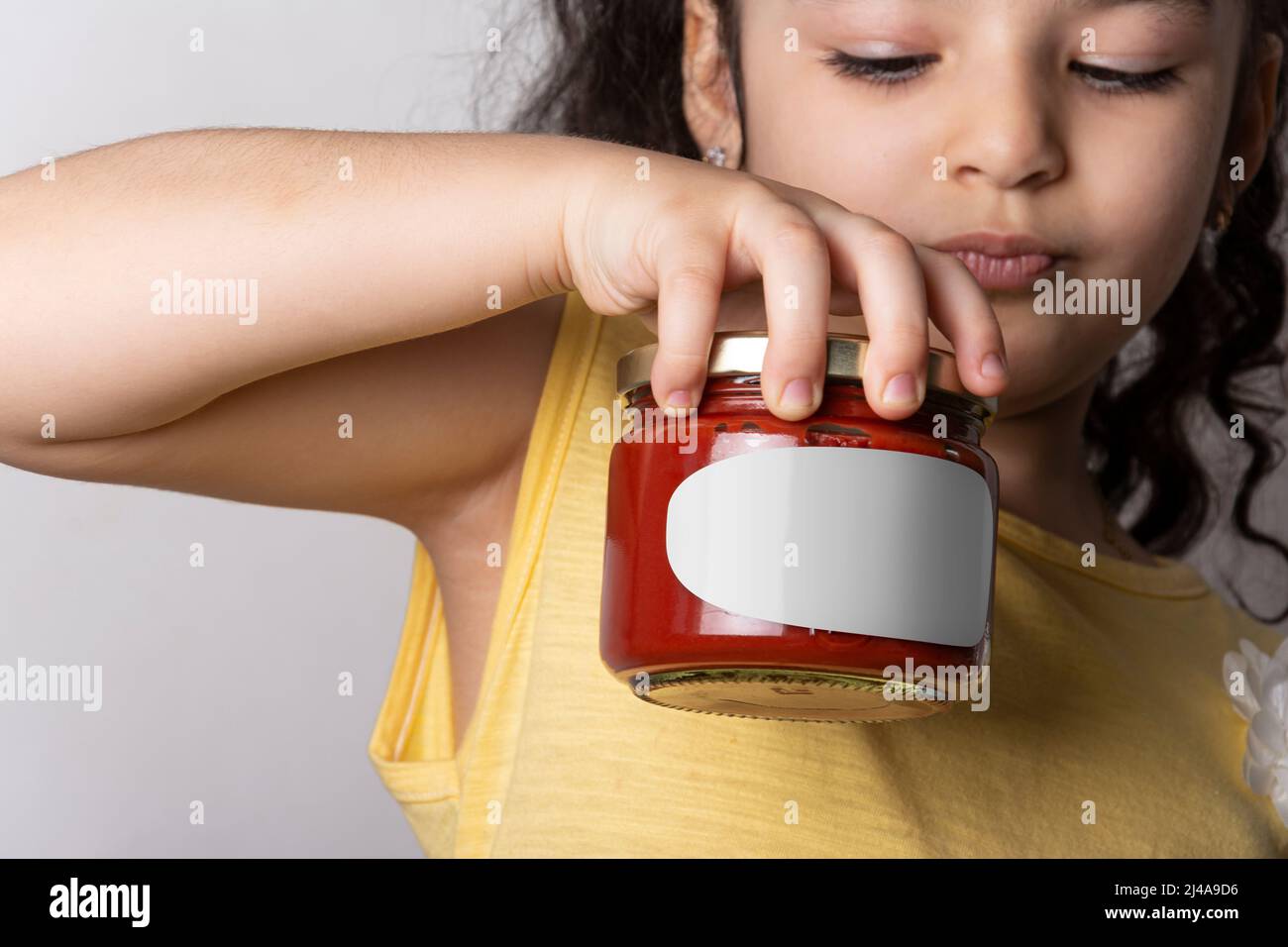 Little girl holding a homemade tomato paste in hand, editable mock-up series template ready for your design. label selection path included. Stock Photo