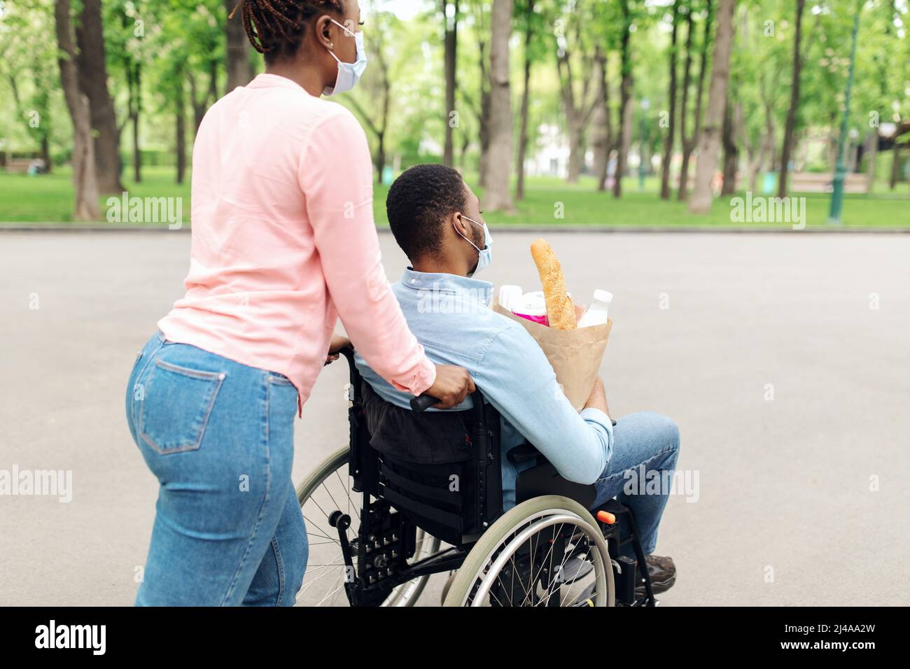 Young black guy in wheelchair holding bag with food, returning home