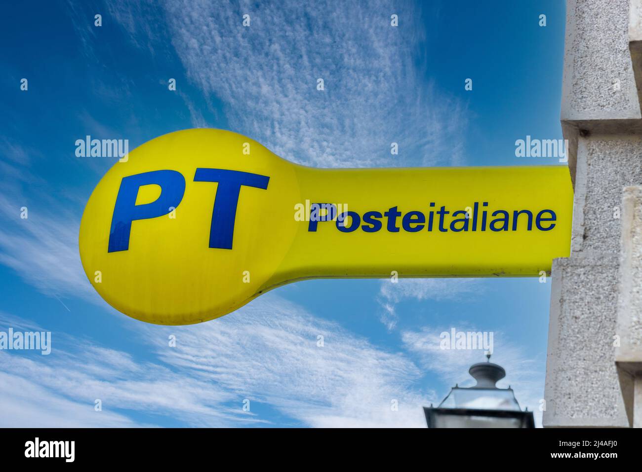 Cuneo, Italy - April 11, 2022: PT Poste Italiane, Italy Post logo on yellow sign on blue sky, outside the Italian post office. Tex: Posteitaliane (Ita Stock Photo