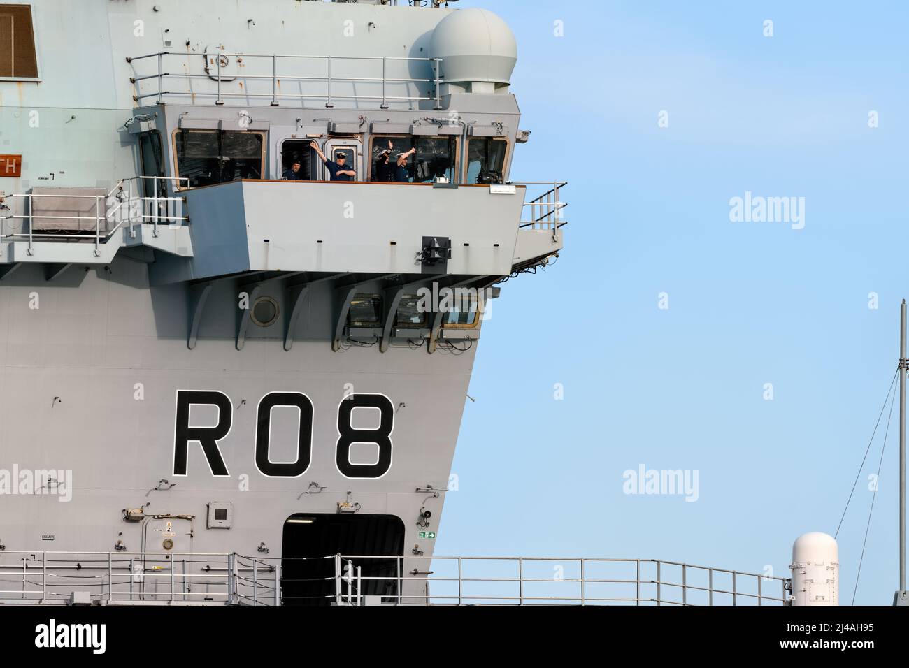Sailors waving from the Royal Navy aircraft carrier HMS Queen Elizabeth (R08) as it sails from Portsmouth Harbour - March 2022. Stock Photo