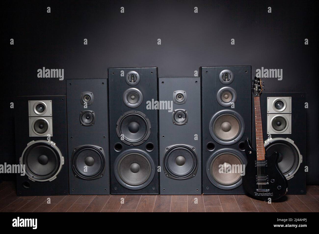 Many assorted audio loudspeakers on a wall lit from above Stock Photo