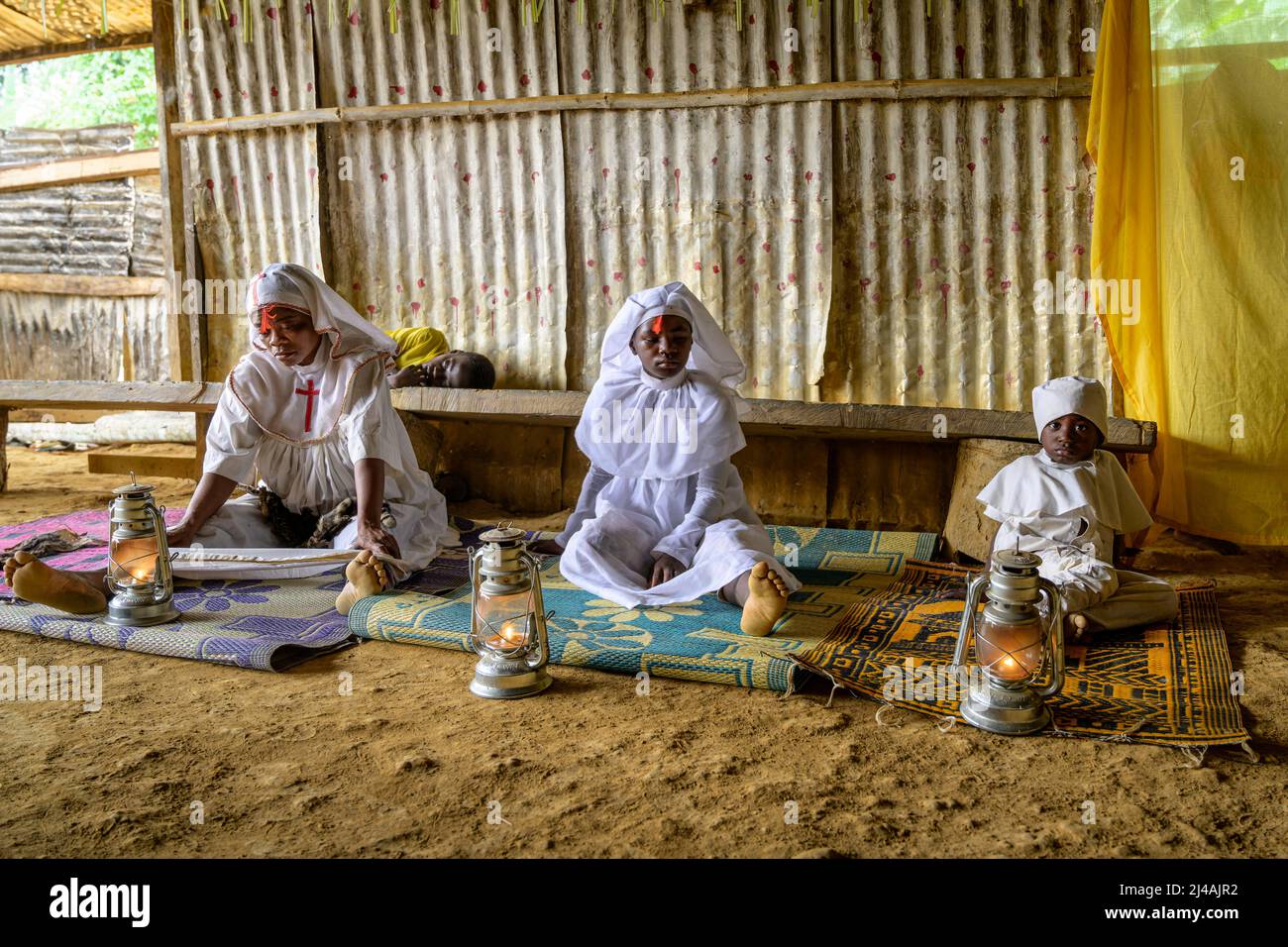 Neophytes dressed in liturgical clothing resting after a long night under the effects of ibogaine during the initiation ceremony in which they will be Stock Photo