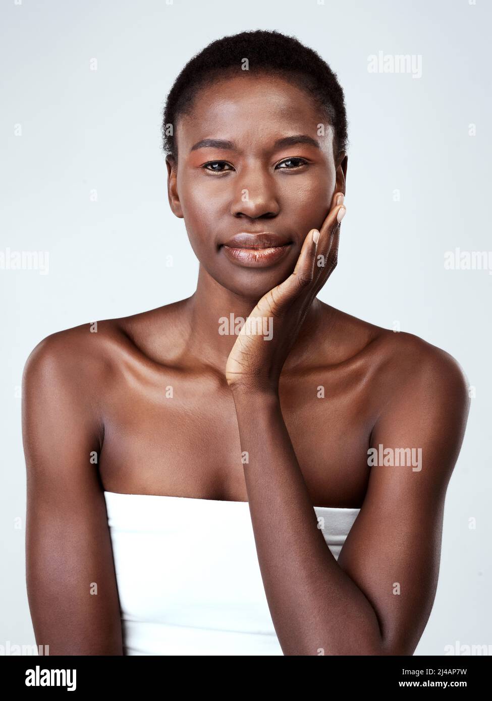 Purely you is purely beautiful. Studio portrait of a beautiful young woman feeling her skin against a grey background. Stock Photo