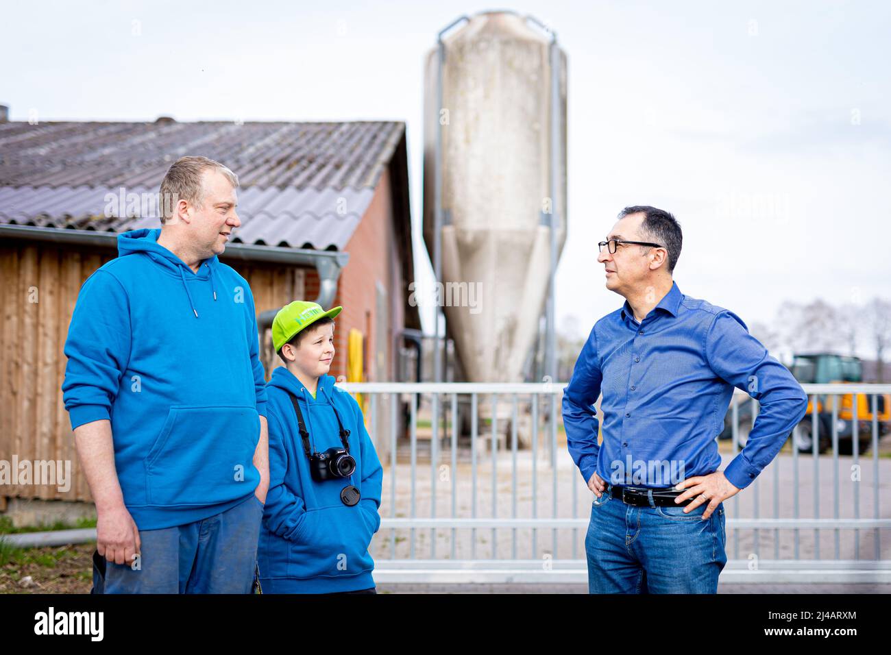 Bergen, Germany. 13th Apr, 2022. Cem Özdemir (r, Bündnis 90/Die Grünen),  Federal Minister of Food and Agriculture, talks to Jan-Hendrik Hohls (l),  farmer, and his son during his visit to a pig