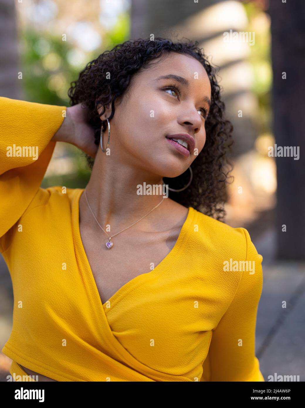 Close up portraits of a young black woman in dappled sunlight seated in a garden Stock Photo
