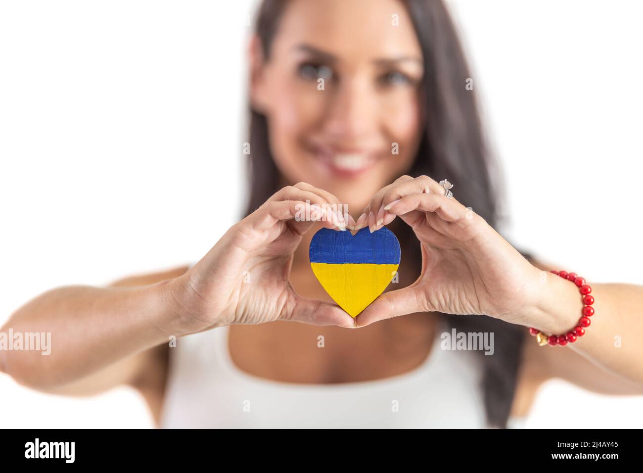 Young activist holding a heart in Ukraine colours representing love and empathy to attacked people. Isolated background. Stock Photo