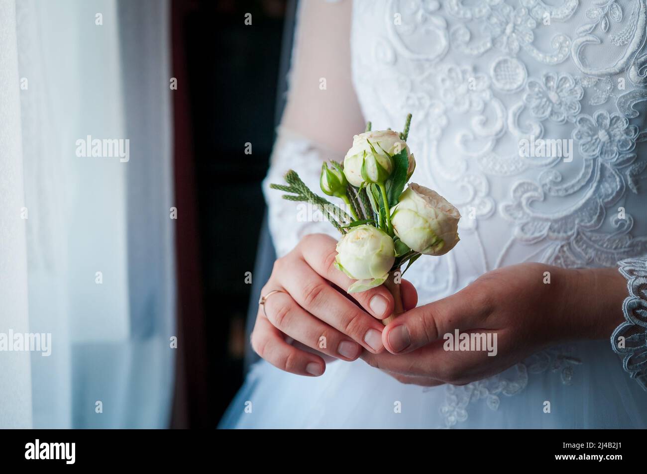 Boutonniere of the groom with flowers in the hands of the bride Stock Photo
