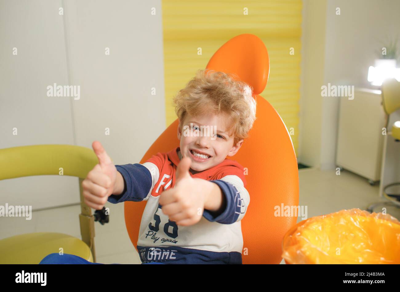 Dental clinic. Smiling boy showing thumbs up sign and looking at camera ...