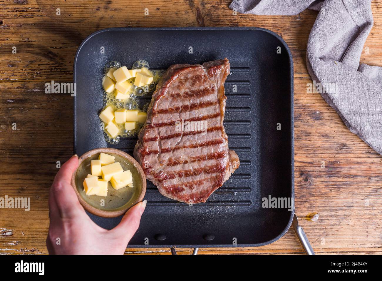 Cooking steak in a griddle pan with butter Stock Photo Alamy