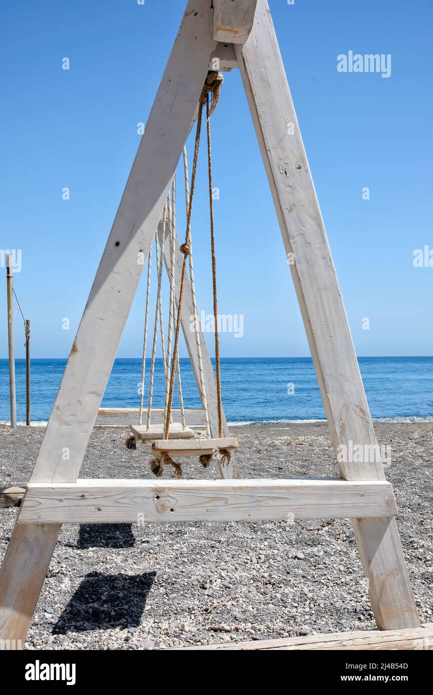 View of a wooden swing on the sandy black beach of Perissa in Santorini Stock Photo