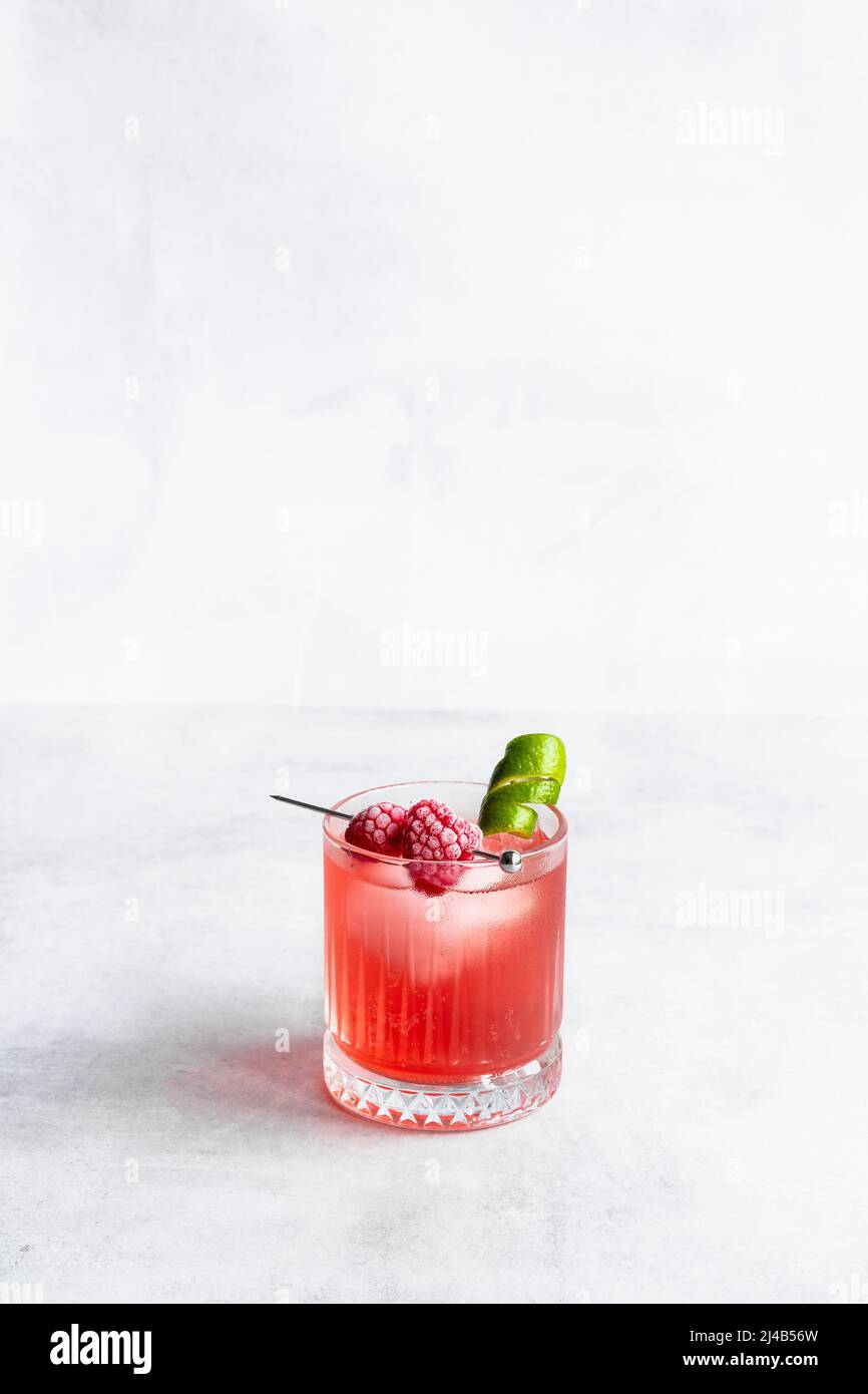 Raspberry and lime cocktail with frozen raspberries and lime garnish. Stock Photo