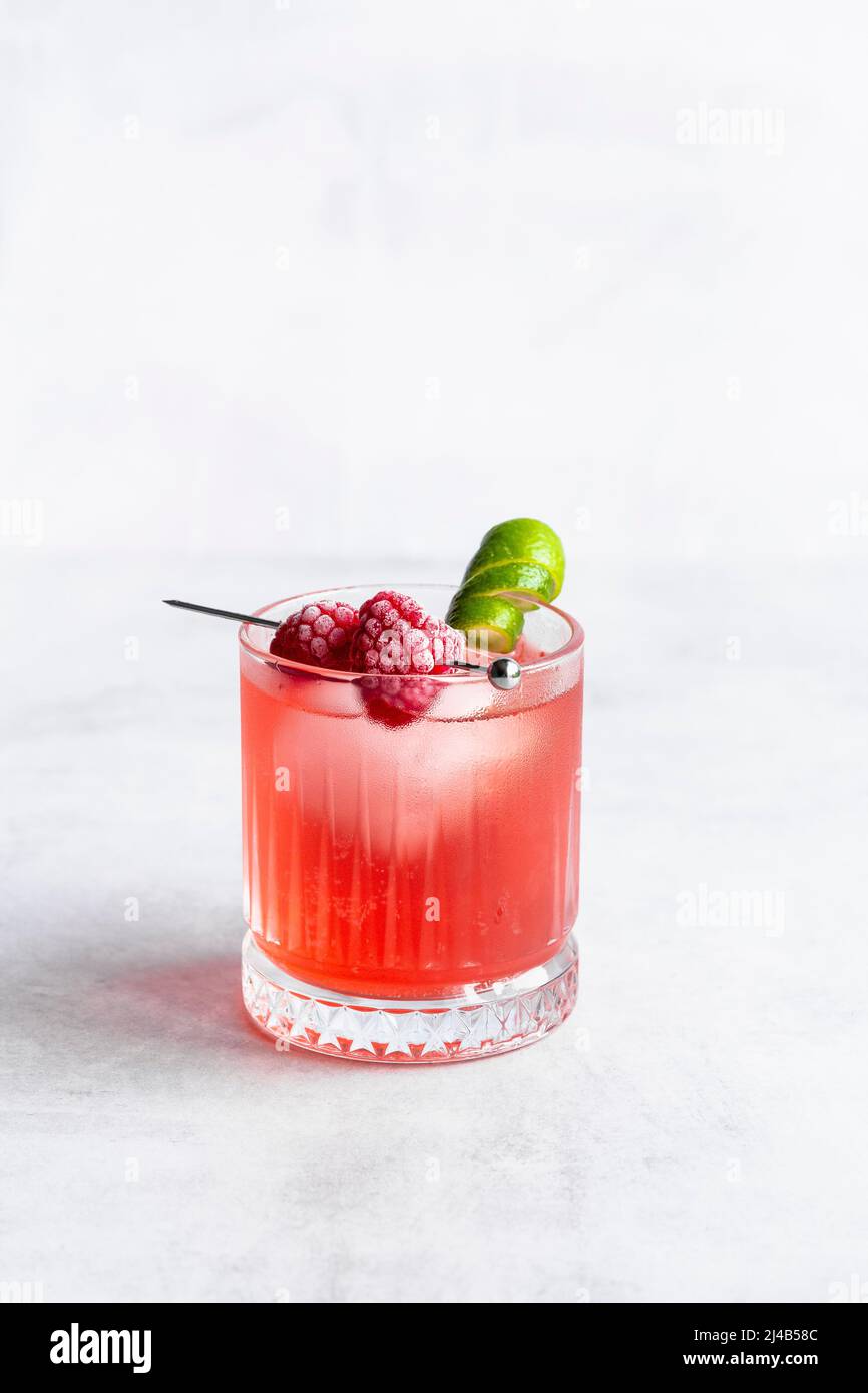 Raspberry and lime cocktail with frozen raspberries and lime garnish. Stock Photo