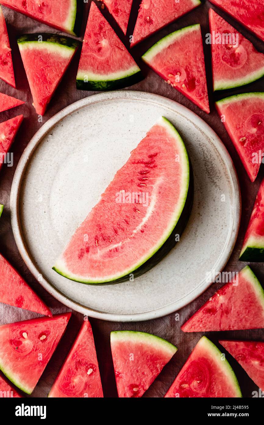 Watermelon slice on a ceramic plate surrounded with smaller watermelon slices. Stock Photo