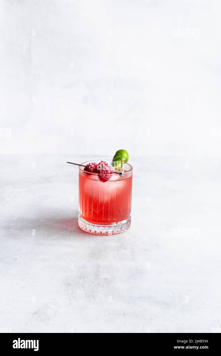 Raspberry and lime cocktail with frozen raspberries and lime garnish. Stock Photo