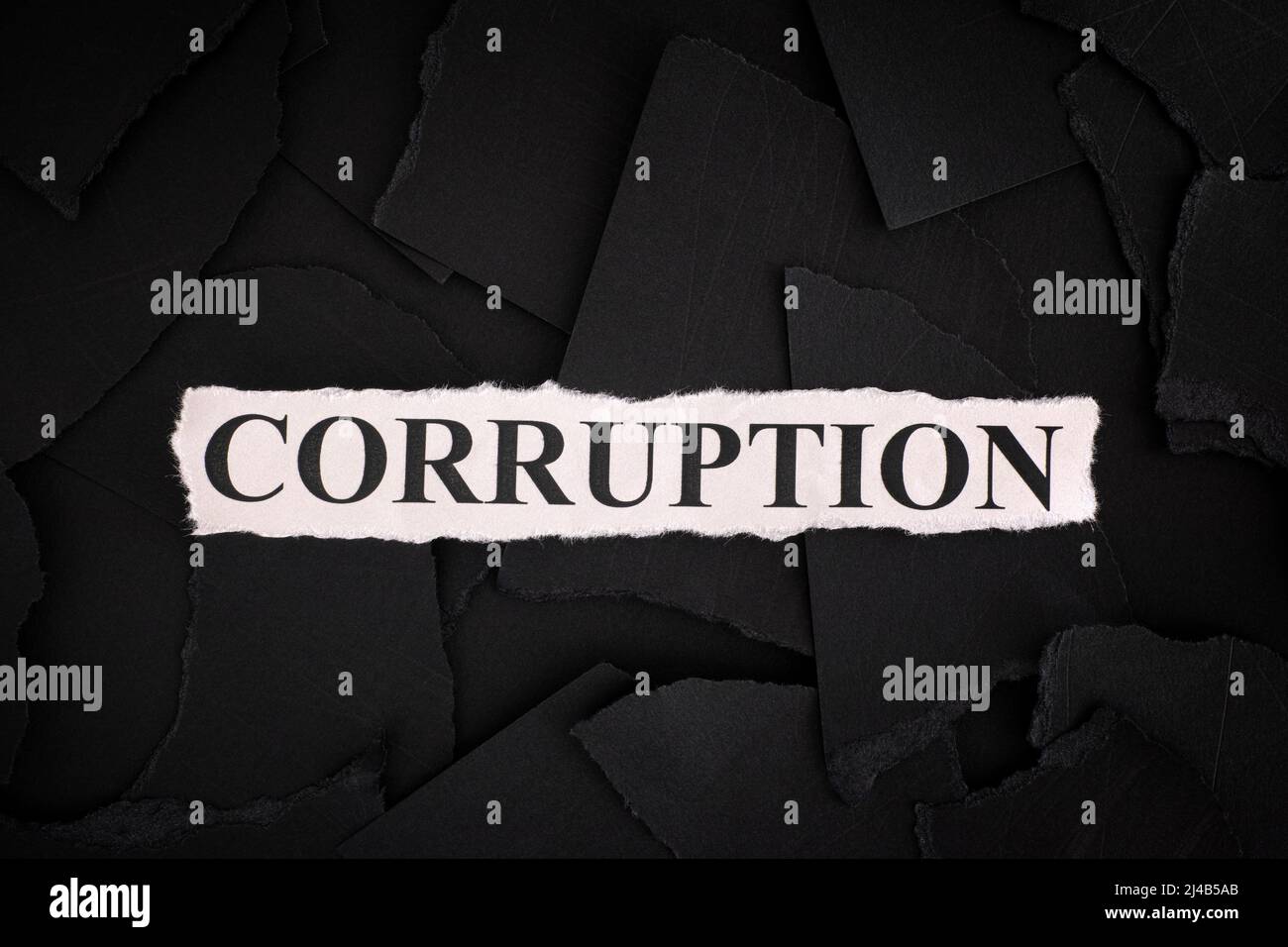 Torn pieces of black paper with the word Corruption. Concept Image. Close up. Stock Photo