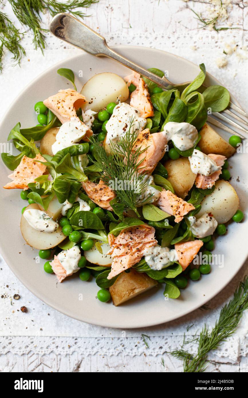 Plate of salad with poached slalmon, boiled potatoes, peas, lambs lettuce and a creamy dill dressing. Stock Photo