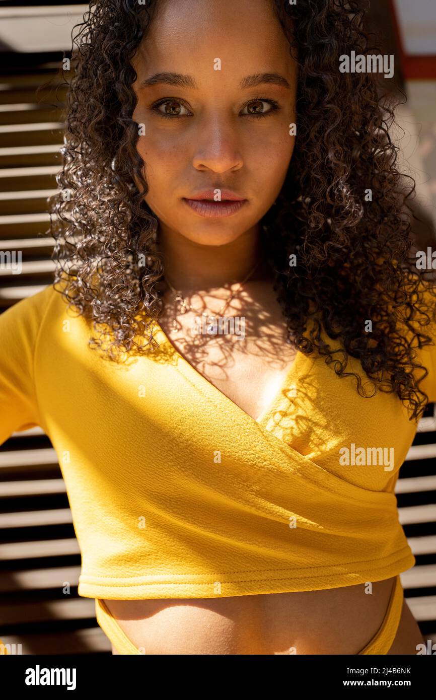 Portrait of a Colorful Young Black Woman Standing in front of Victorian Shutters Stock Photo