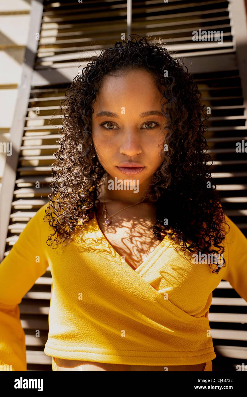 Portrait of a Colorful Young Black Woman Standing in front of Victorian Shutters Stock Photo