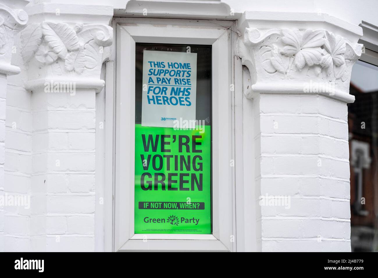 Posters in the window of a residential property relating to forthcoming local elections. Supporting the Green Party and NHS pay rise Stock Photo