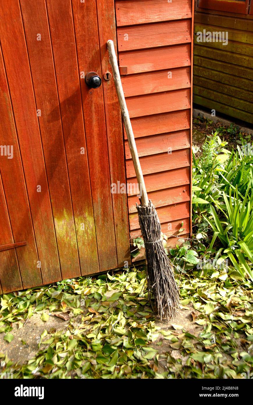 Besom broom leaning against wooden garden shed Stock Photo