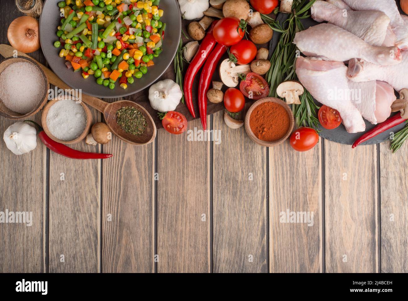 Vegetables with raw chicken legs on a wooden texture. Top view, with an