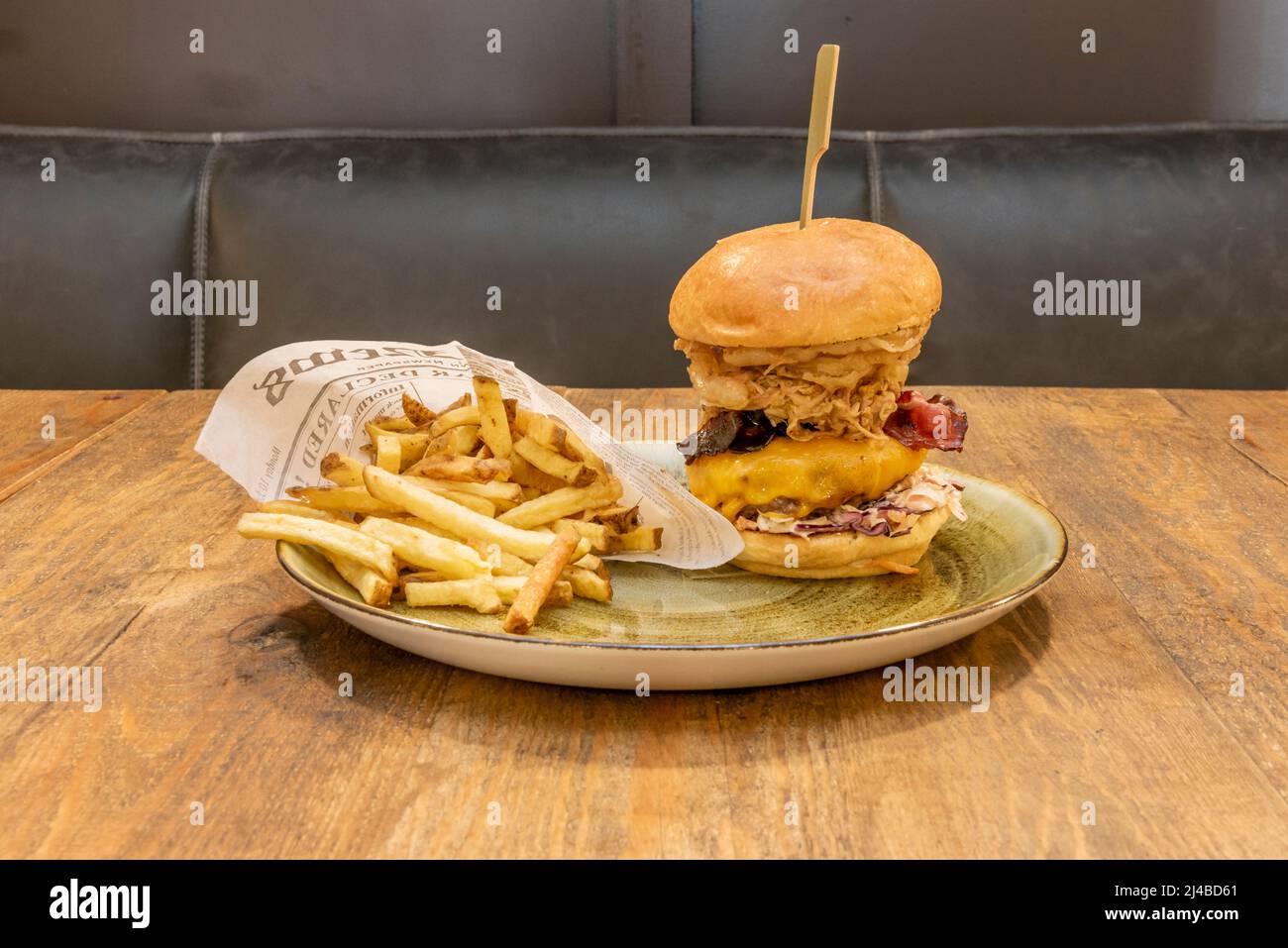 Crispy multi-tiered beef and chicken burger with tomato, lettuce, melted cheddar cheese, fried bacon, fried onion rings, brie cheese and a large porti Stock Photo