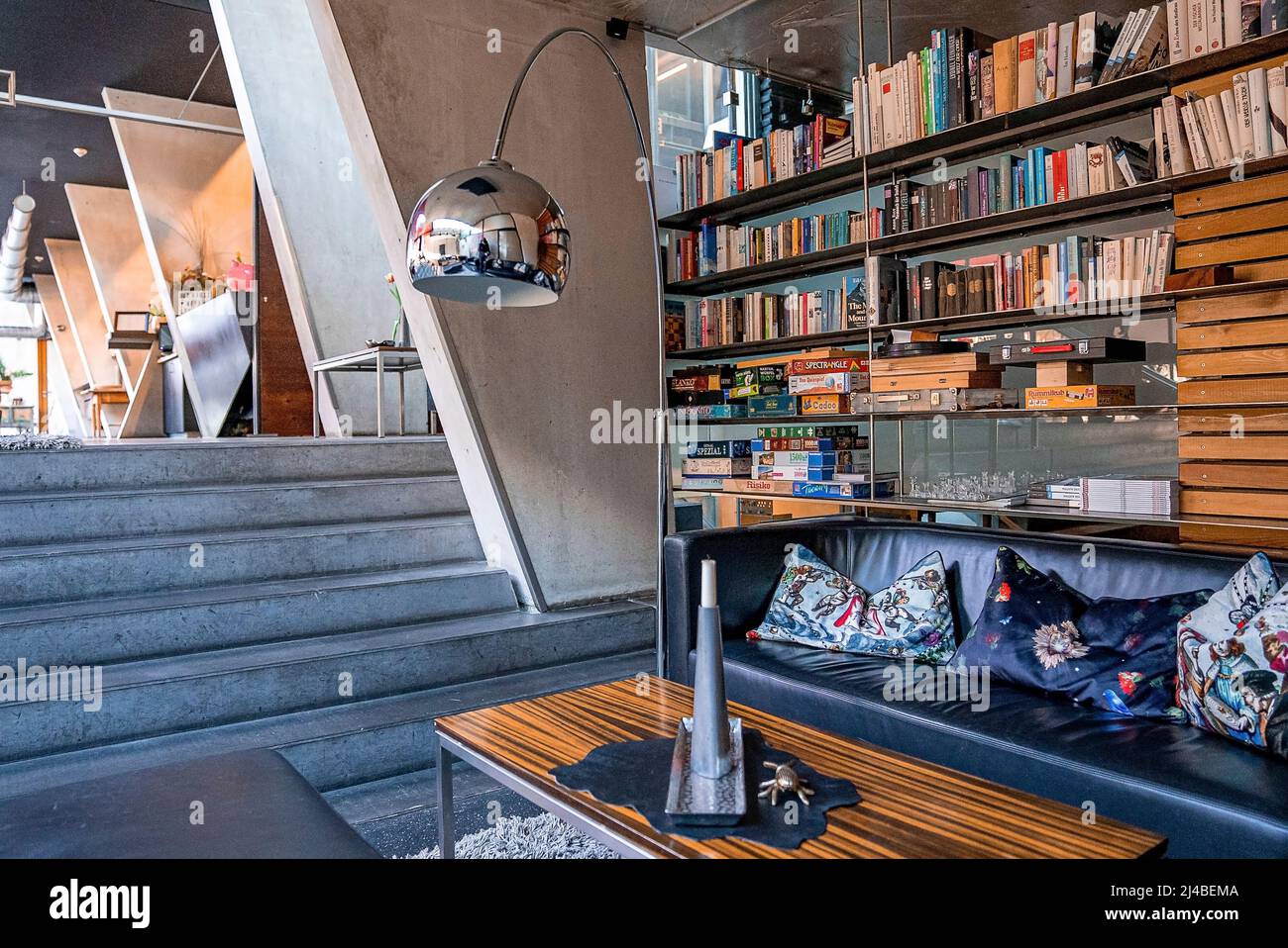 Comfortable sofa with pillows and bookshelves in library at hotel lobby Stock Photo