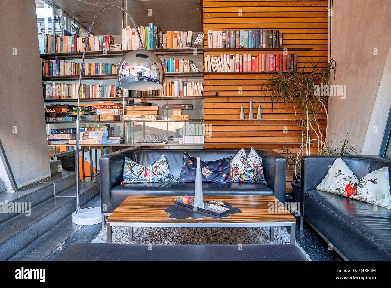 Comfortable sofa with pillows and bookshelves in library at hotel lobby Stock Photo