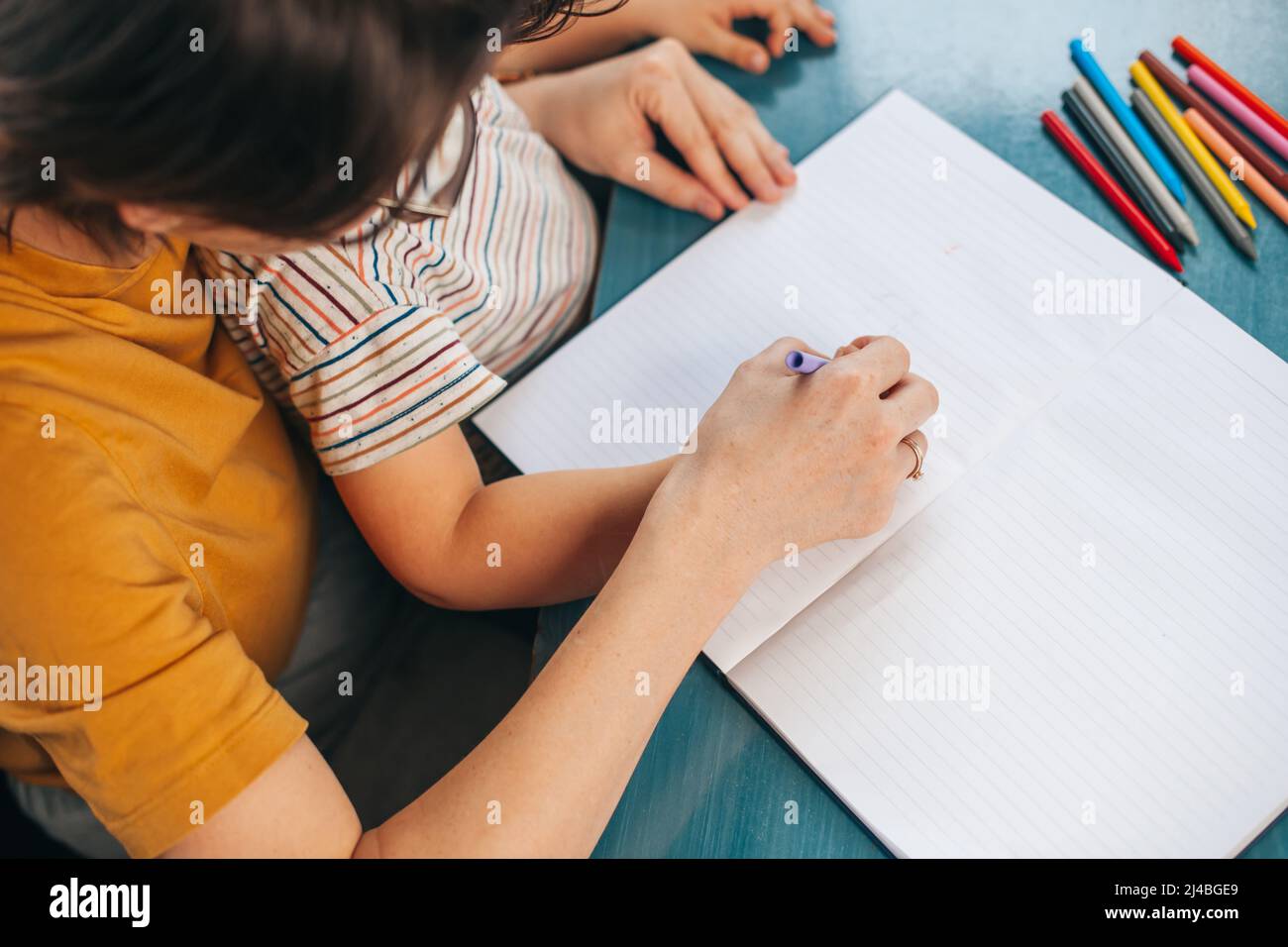 Top view of a mom helping her son kid with homework and exercises ...