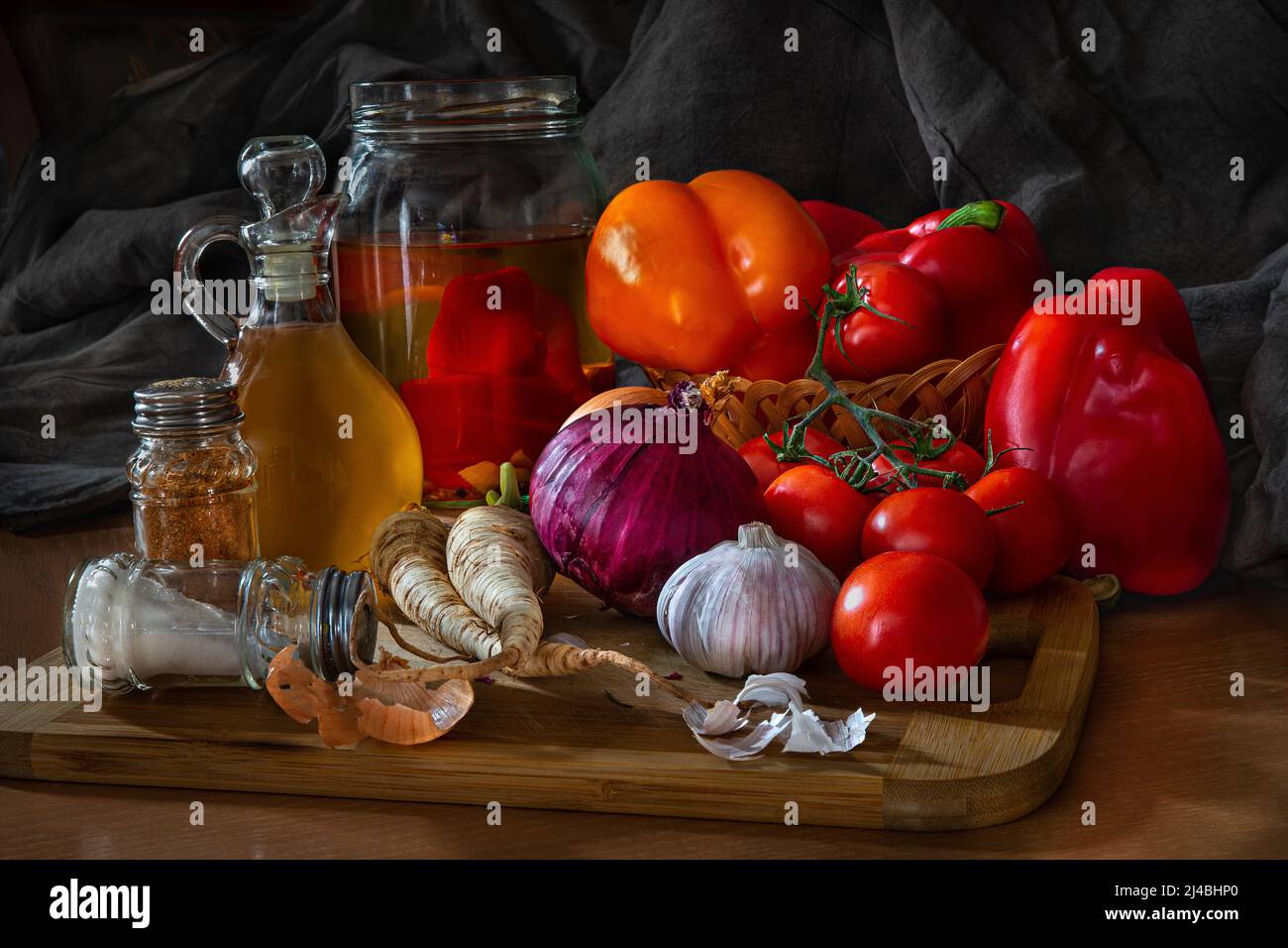 Dark and atmospheric still life photo, vegetables, red pepper, yellow pepper, olive oil, parsley root, salt shaker, spices, made using natural light. Stock Photo