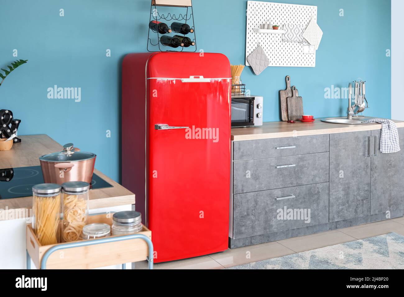 Interior of stylish kitchen with red fridge, counters and pegboard