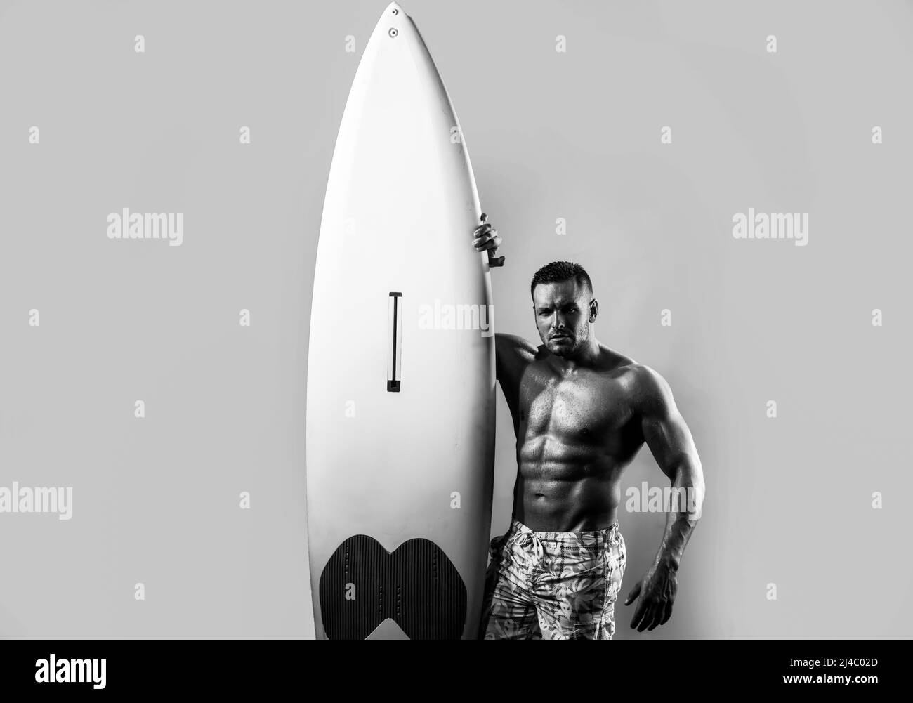Handsome serfer man with serf board. Male fit with athletic body. Surfboard man with serf board. Surfer with a surfboard isolated on blue. Stock Photo