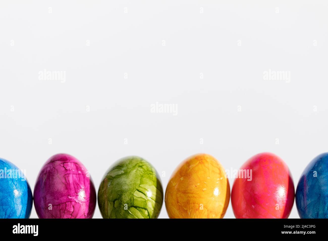 Many Easter eggs arranged in one row on a white background. Easter. Stock Photo