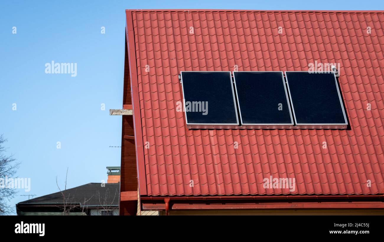 Solar energy. Water solar collector on a red metal roof Stock Photo - Alamy