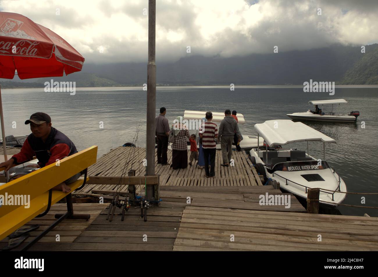 Domestic tourists at the jetty of Bedugul water sport recreational area in Bratan lake, Bedugul, Tabanan, Bali, Indonesia. Bratan lake is one of the four lakes—along with Buyan, Tamblingan and Batur—that are supporting the lives of Balinese people. Stock Photo