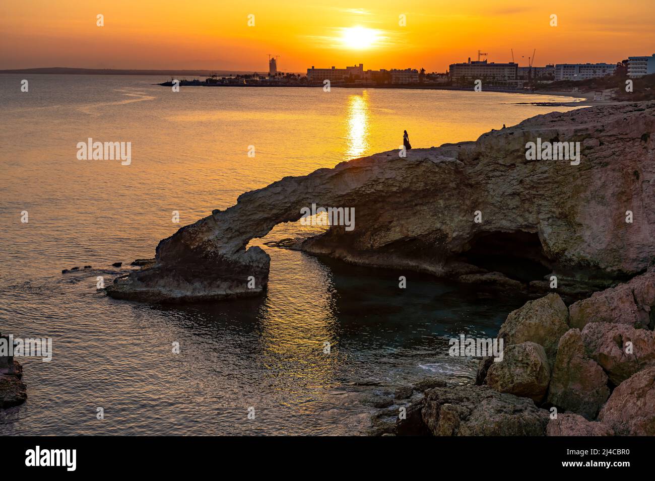 Junge Frau auf der natürlichen Felsenbrücke Love Bridge im Sonnenuntergang, Agia Napa, Zypern, Europa  | young woman posing on the natural  stone brid Stock Photo