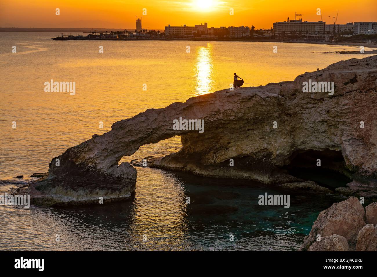 Junge Frau auf der natürlichen Felsenbrücke Love Bridge im Sonnenuntergang, Agia Napa, Zypern, Europa  | young woman posing on the natural  stone brid Stock Photo