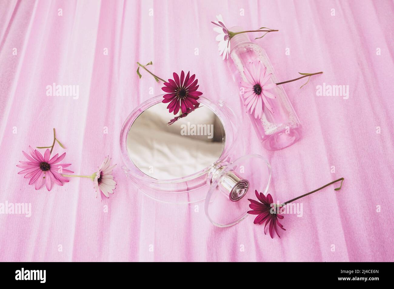Still life of cosmetics with fresh flowers and a mirror in pink tones Stock Photo