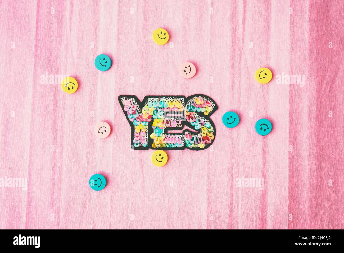 Word 'yes' make with colorful sequins and surrounded by smiley faces Stock Photo