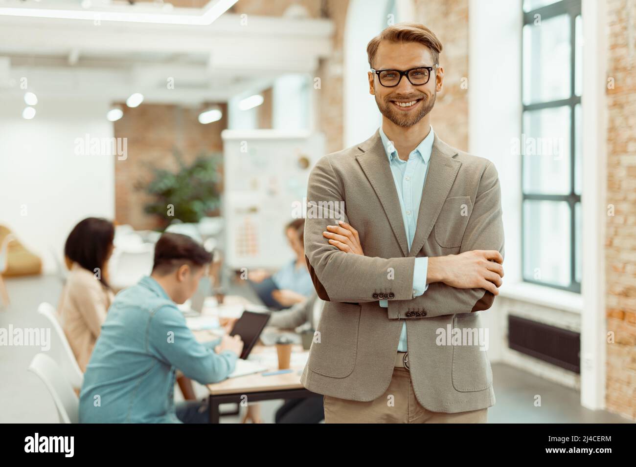 Smiling man standing in a coworking space and clasped his hands Stock Photo