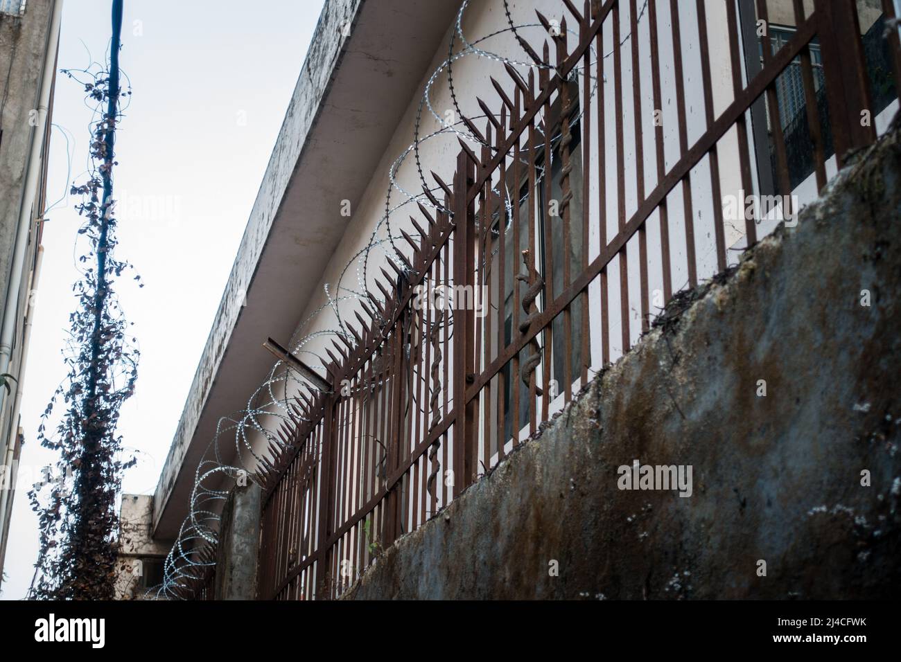 Barbed wire enclosure outside a building with metal grill Stock Photo