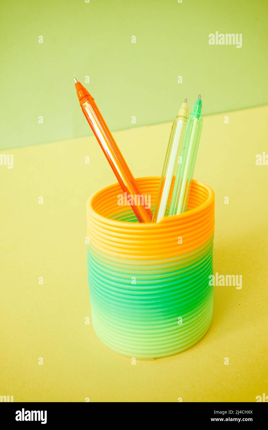 Colorful pens inside a colorful slinky toy Stock Photo