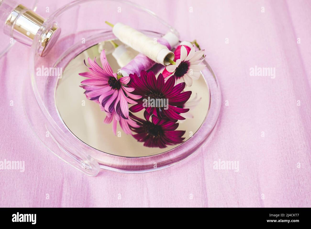 Still life of flowers, sewing threads and a beauty mirror in trendy seasonal tones Stock Photo