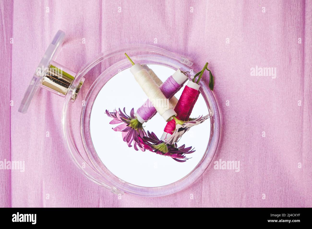 Still life of flowers, sewing threads and a beauty mirror in trendy seasonal tones Stock Photo