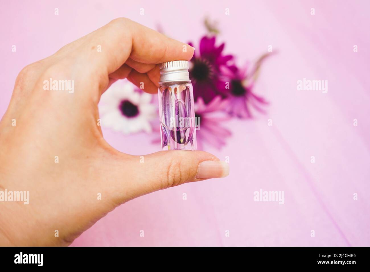 Close up of a hand holding an aromatherapy bottle filled with water and petals Stock Photo