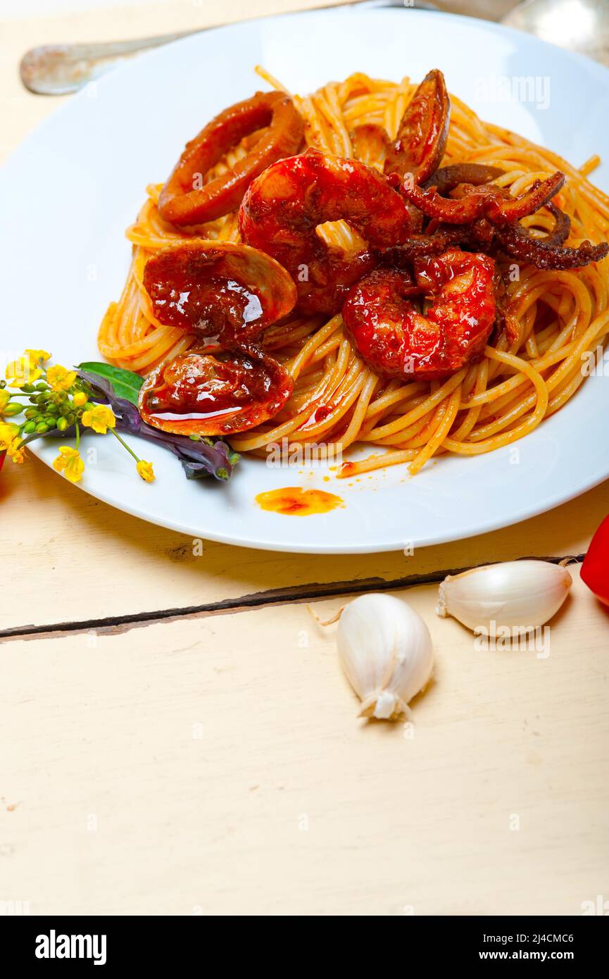 Italian seafood spaghetti pasta on red tomato sauce over white rustic