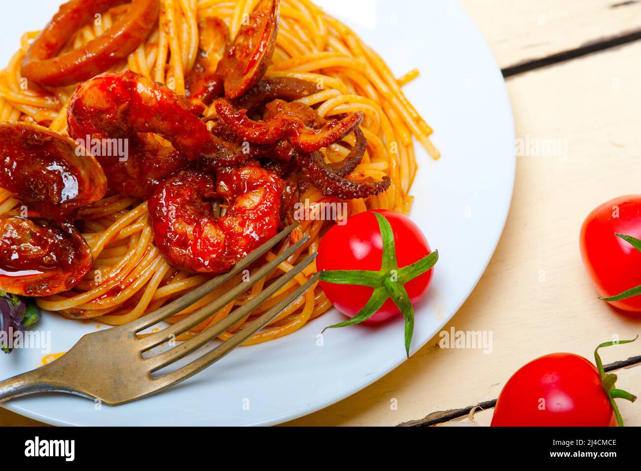 Italian seafood spaghetti pasta on red tomato sauce over white rustic