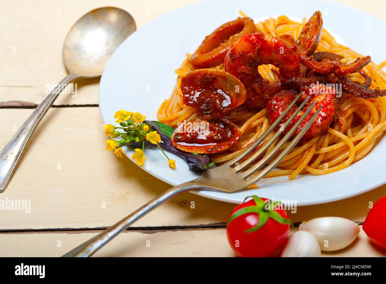 Italian seafood spaghetti pasta on red tomato sauce over white rustic