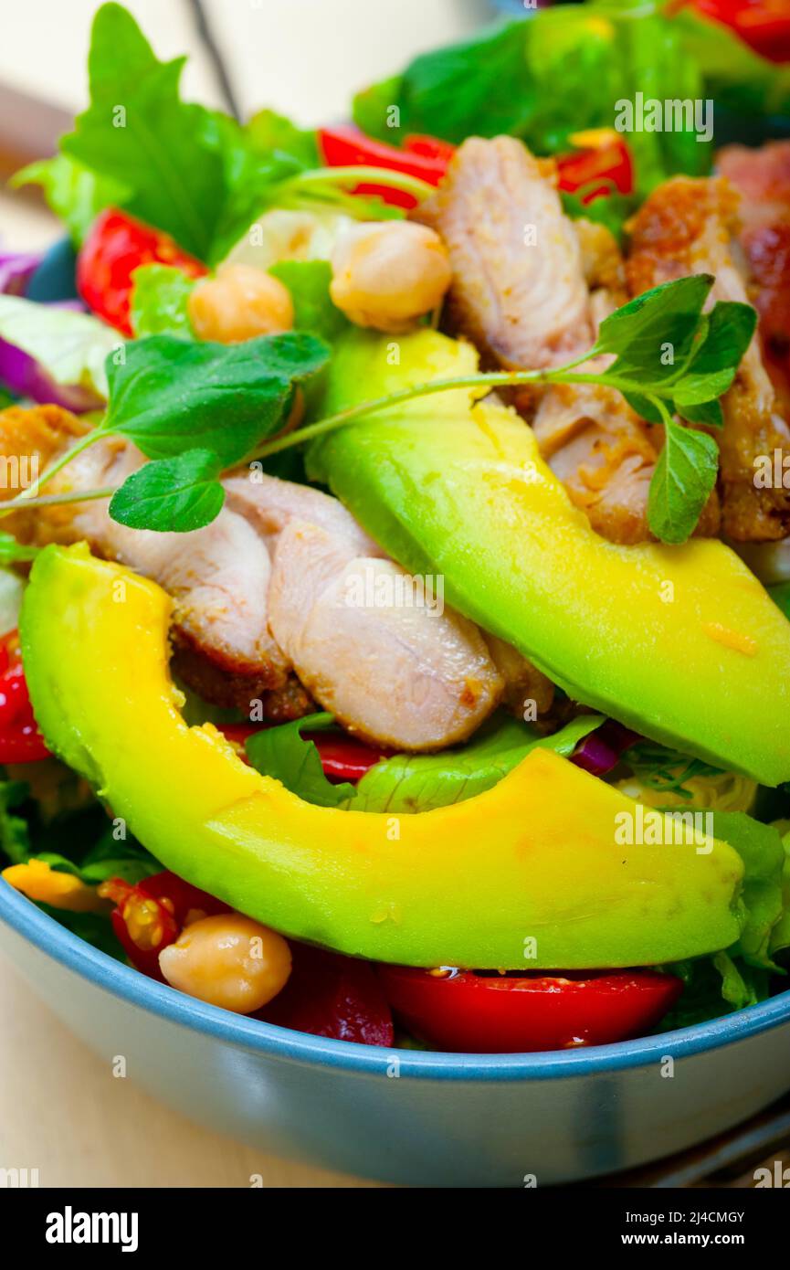 Fresh and healthy chicken avocado salad over rustic wood table stock